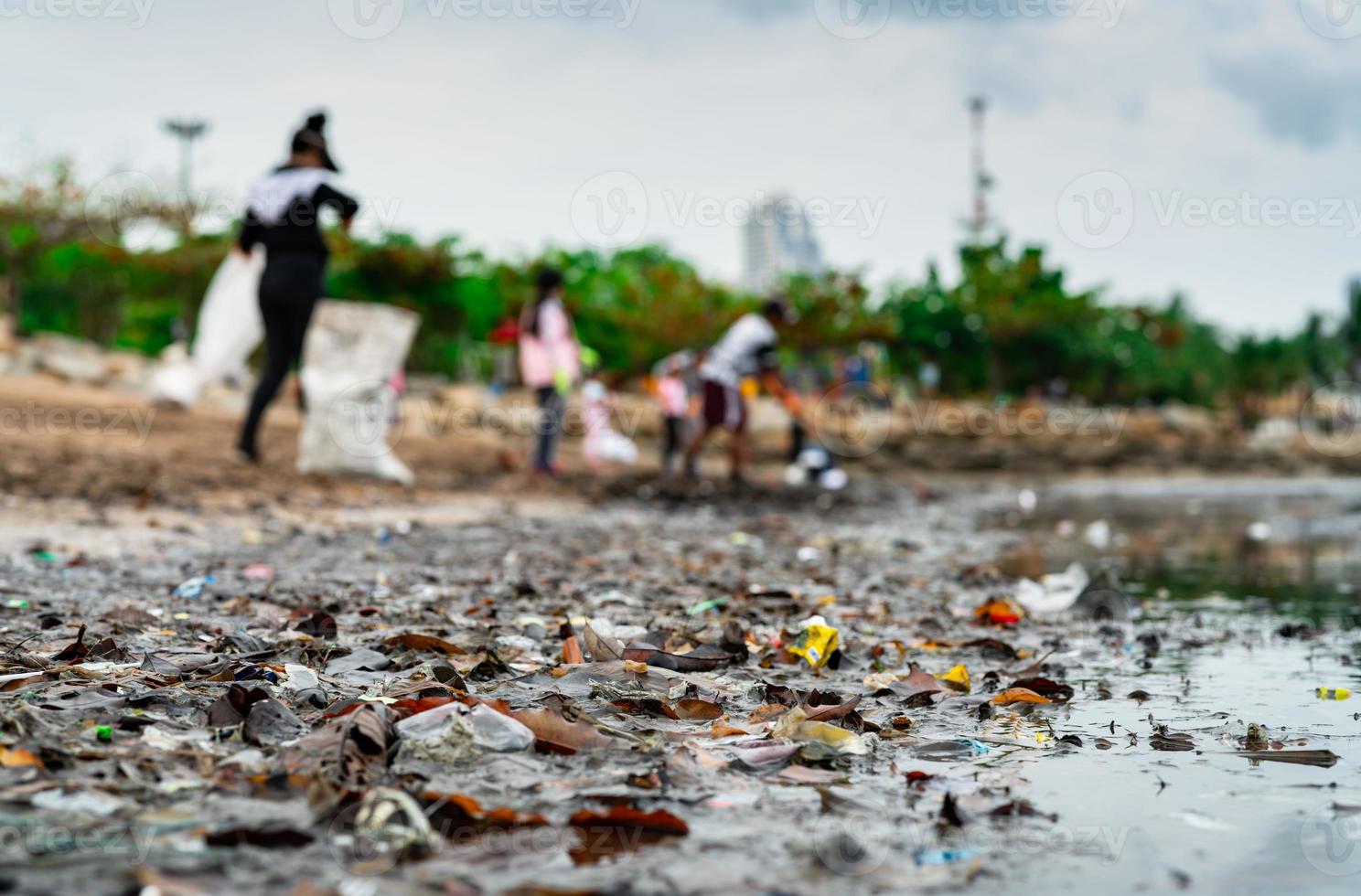 wazig van vrijwilligers die afval verzamelen. strand milieu vervuiling. vrijwilligers die het strand schoonmaken. afval opruimen op het strand. olievlekken op het strand. olielek naar zee. foto