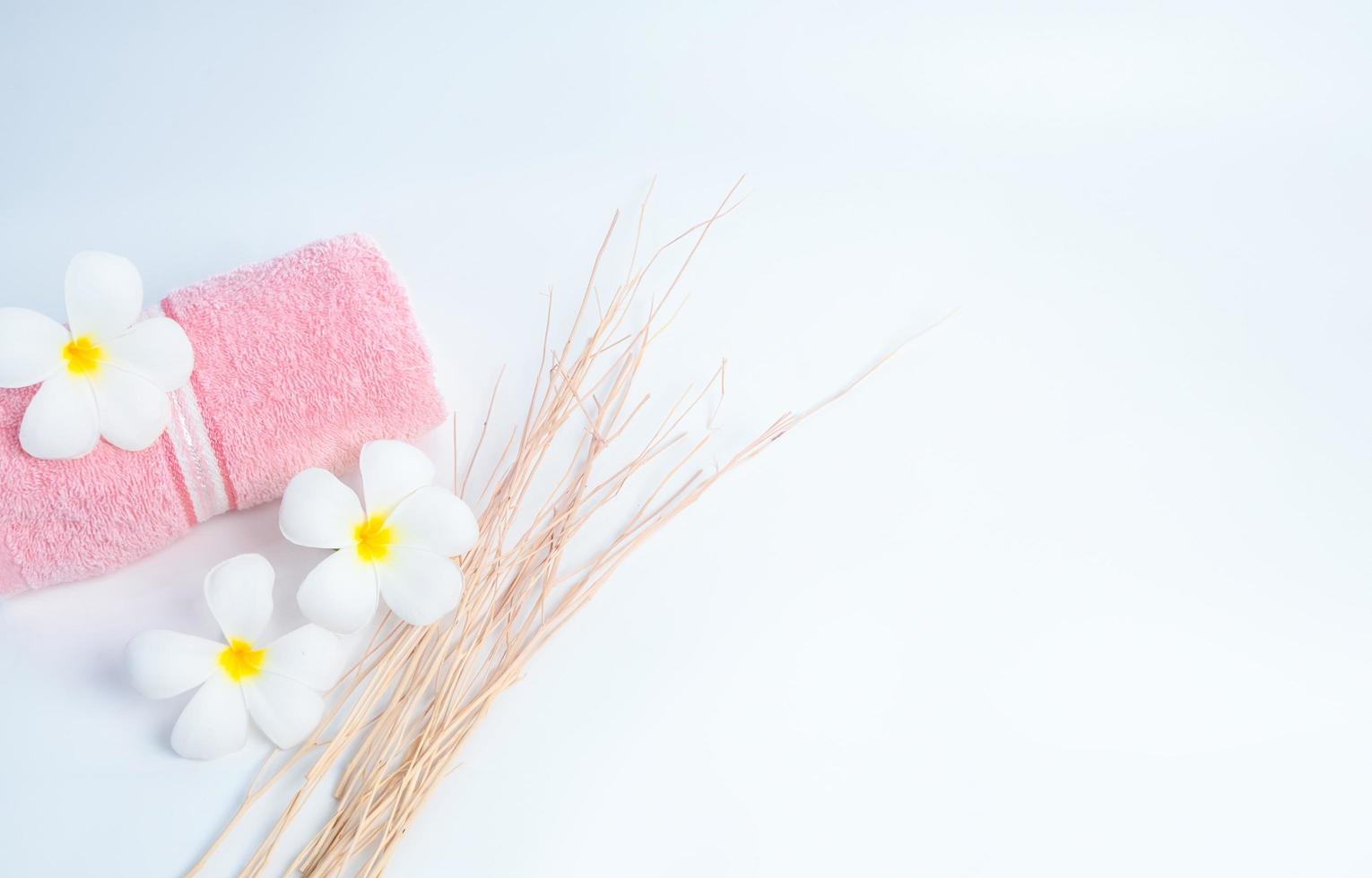 gerold roze spa handdoek en frangipani bloemen met tak op witte achtergrond. spa- en wellnesscentrum van het hotel of resort. achtergrond voor bad- en schoonheidsproducten. ontspannen met aromatherapie. zen. foto