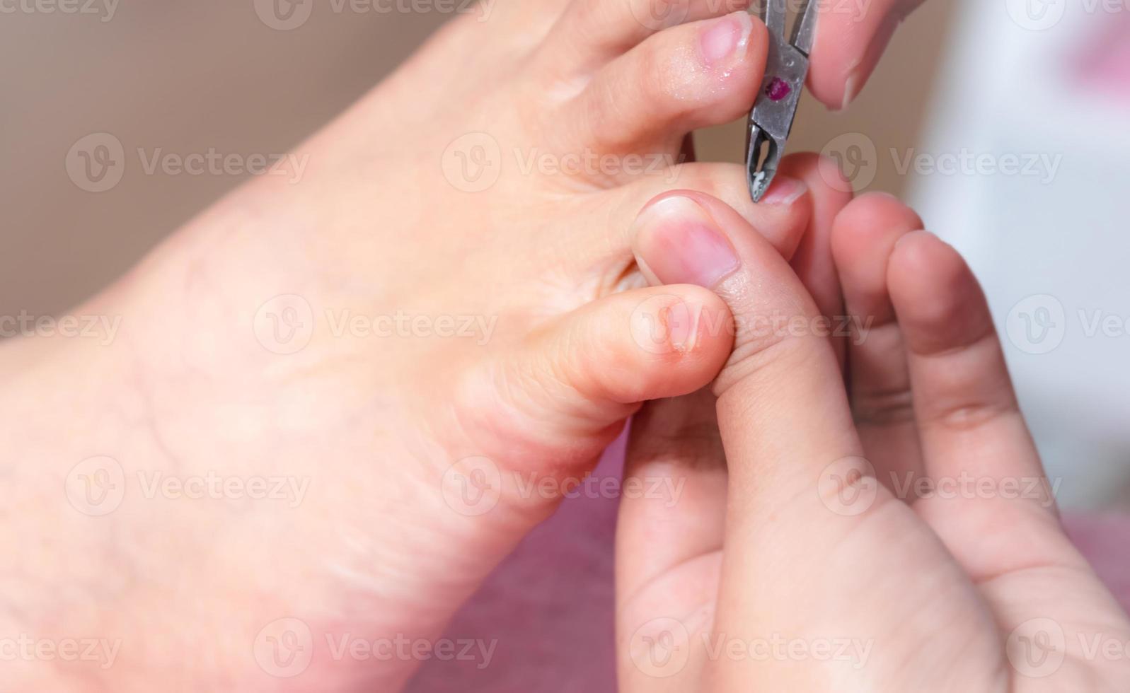 vrouw die nagel-pedicure-service ontvangt door professionele pedicure bij nagelsalon. schoonheidsspecialiste gebruikt clipper voor het reinigen en knippen van de nagelriem bij nagel- en spasalon. voet- en nageltherapie door therapeut. foto