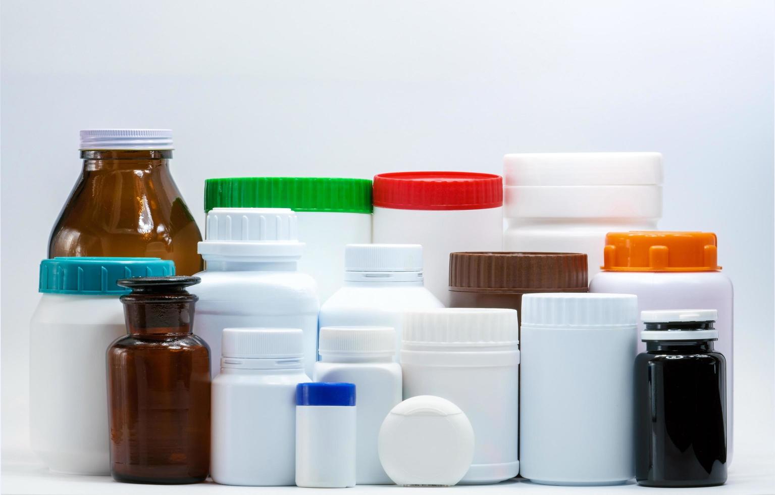 medische plastic en amberkleurige fles op witte achtergrond met blanco label. farmaceutische verpakkingsindustrie. vitamine en supplement fles container. pillenfles met oranje, groene, blauwe en rode dop. foto