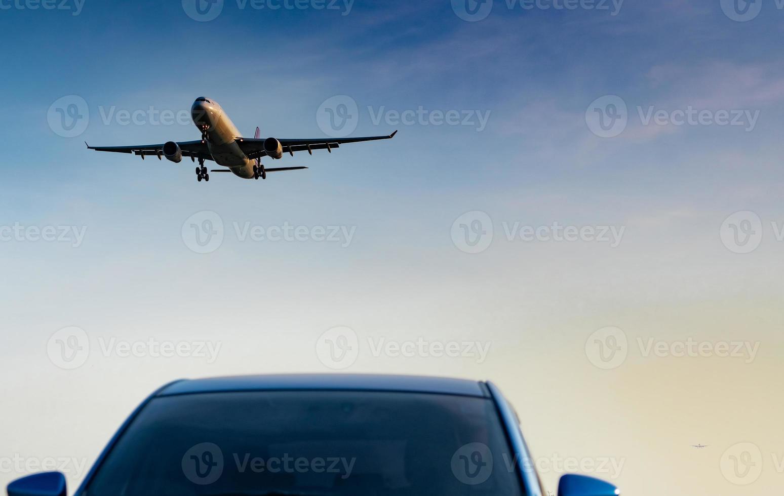 commerciële luchtvaartmaatschappij. passagiersvliegtuig landing nadering blauwe suv auto op luchthaven met blauwe lucht en wolken bij zonsondergang. Aankomst Vlucht. vakantietijd. fijne reis. vliegtuig dat op heldere hemel vliegt. auto geparkeerd. foto