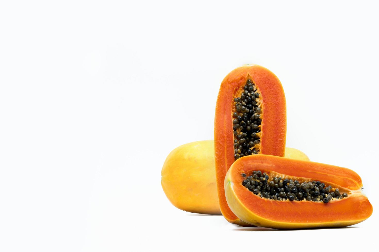 geheel en de helft van rijpe papaya fruit met zaden geïsoleerd op een witte achtergrond met kopie ruimte. natuurlijke bron van vitamine C, foliumzuur en mineralen. gezonde voeding voor zwangere vrouwen en vrouwen die borstvoeding geven foto