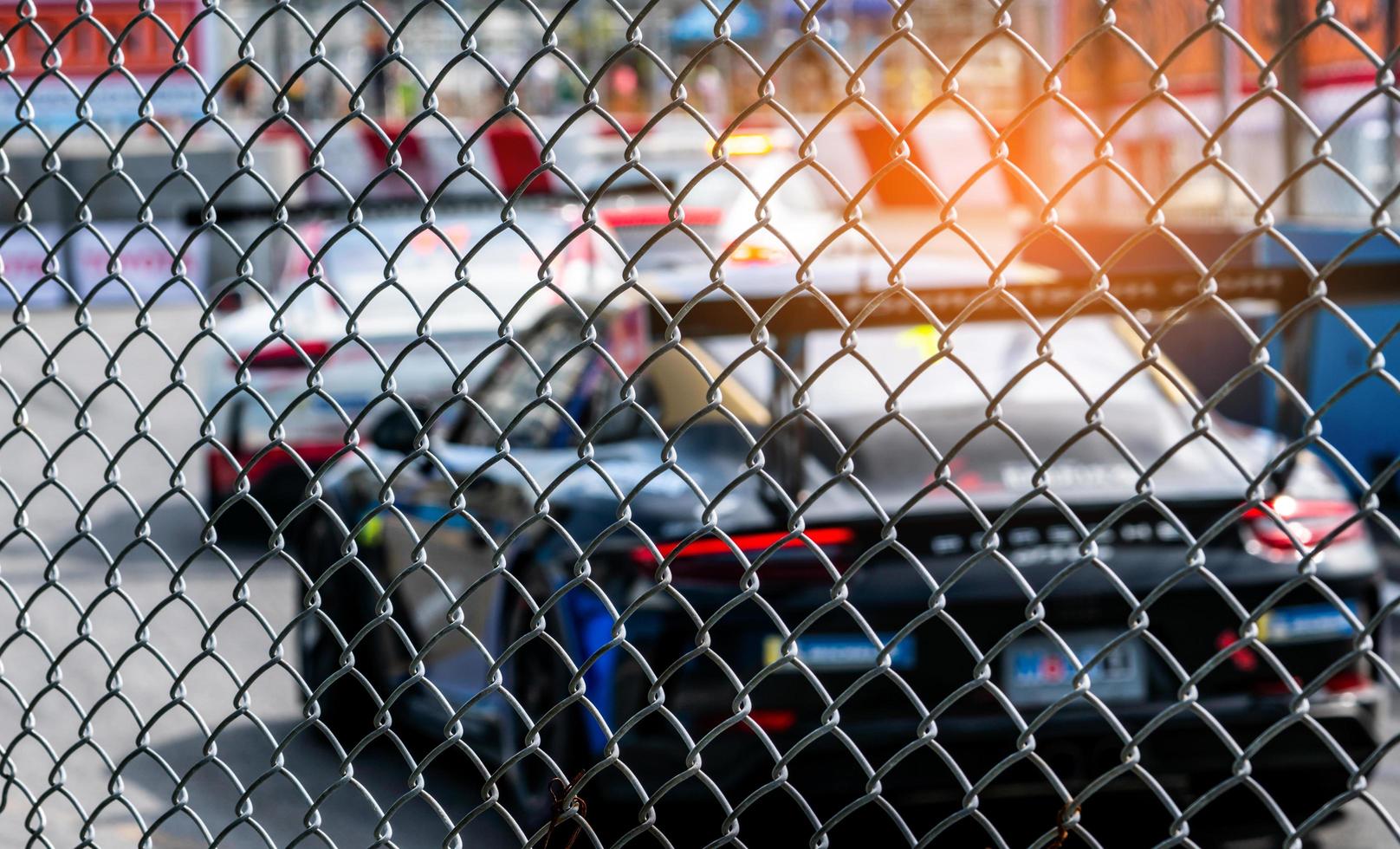 motorsport auto racen op asfaltweg. uitzicht vanaf het hek mesh verrekening op wazig auto op racebaan achtergrond. super racewagen op stratencircuit. auto-industrie concept. foto