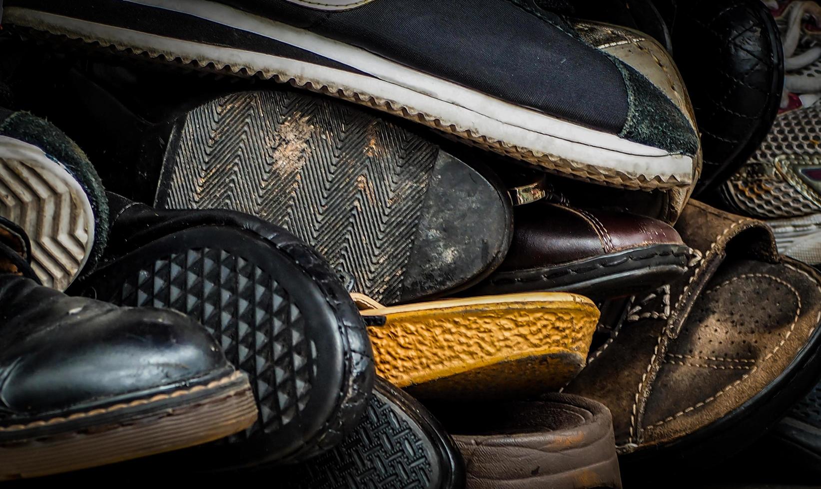 close-up van oude vuile mannelijke schoenen. gebruikte schoenen. hoop oude schoenen. veel vuile mannenschoenen. heren schoenen collectie met niet georganiseerd. mannen houden schoen met wanorde. heren schoenen. foto