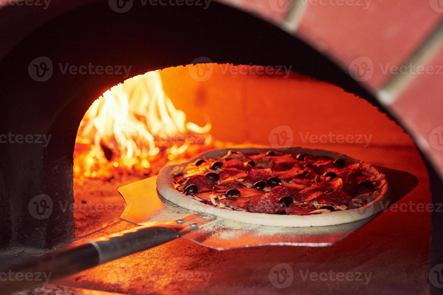 pizza op de showel. vuur dat in de oven brandt. close-up van hout in vlammen foto