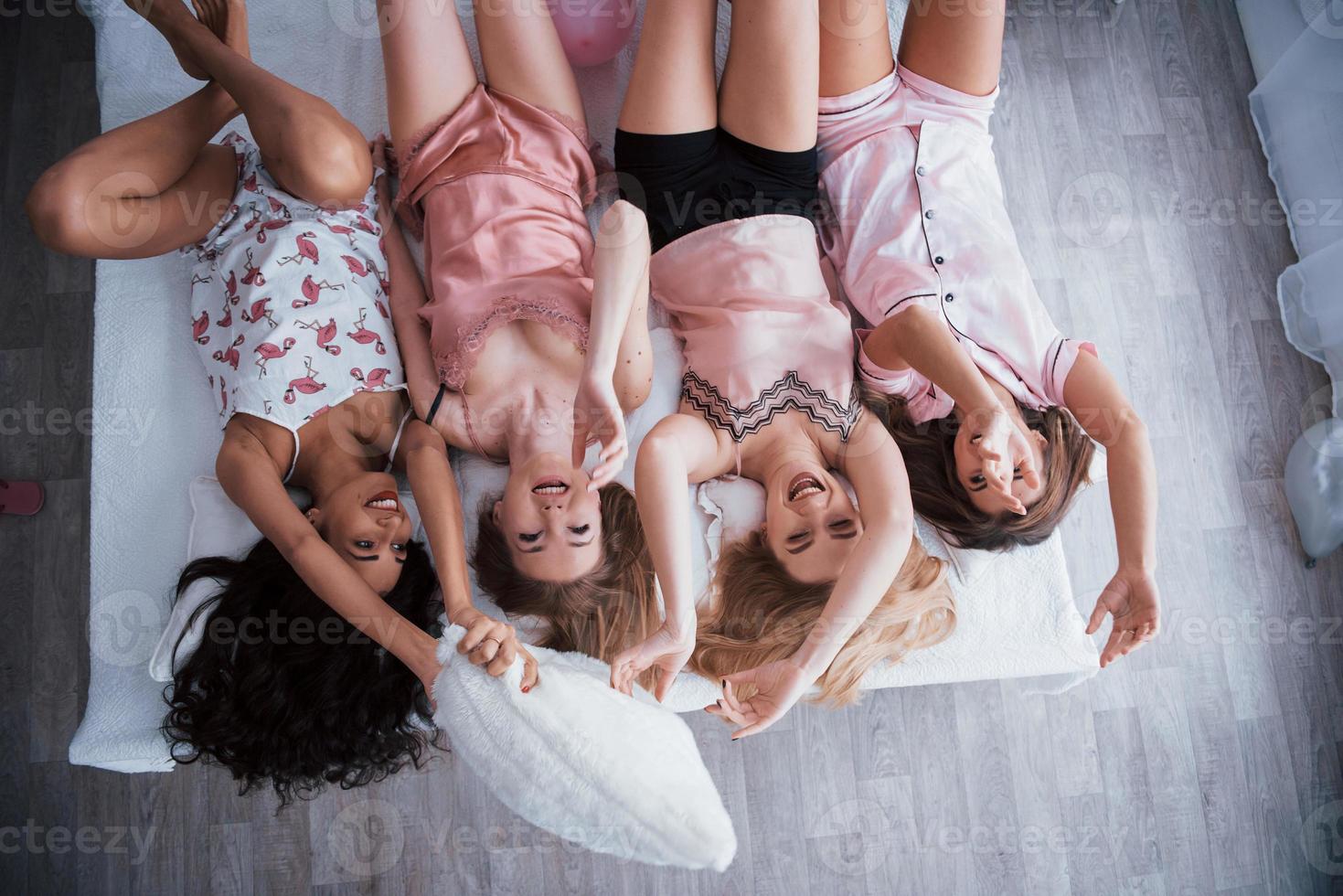 daglicht in de kamer. omgekeerd portret van charmante meisjes die in nachtkleding op bed liggen. bovenaanzicht foto