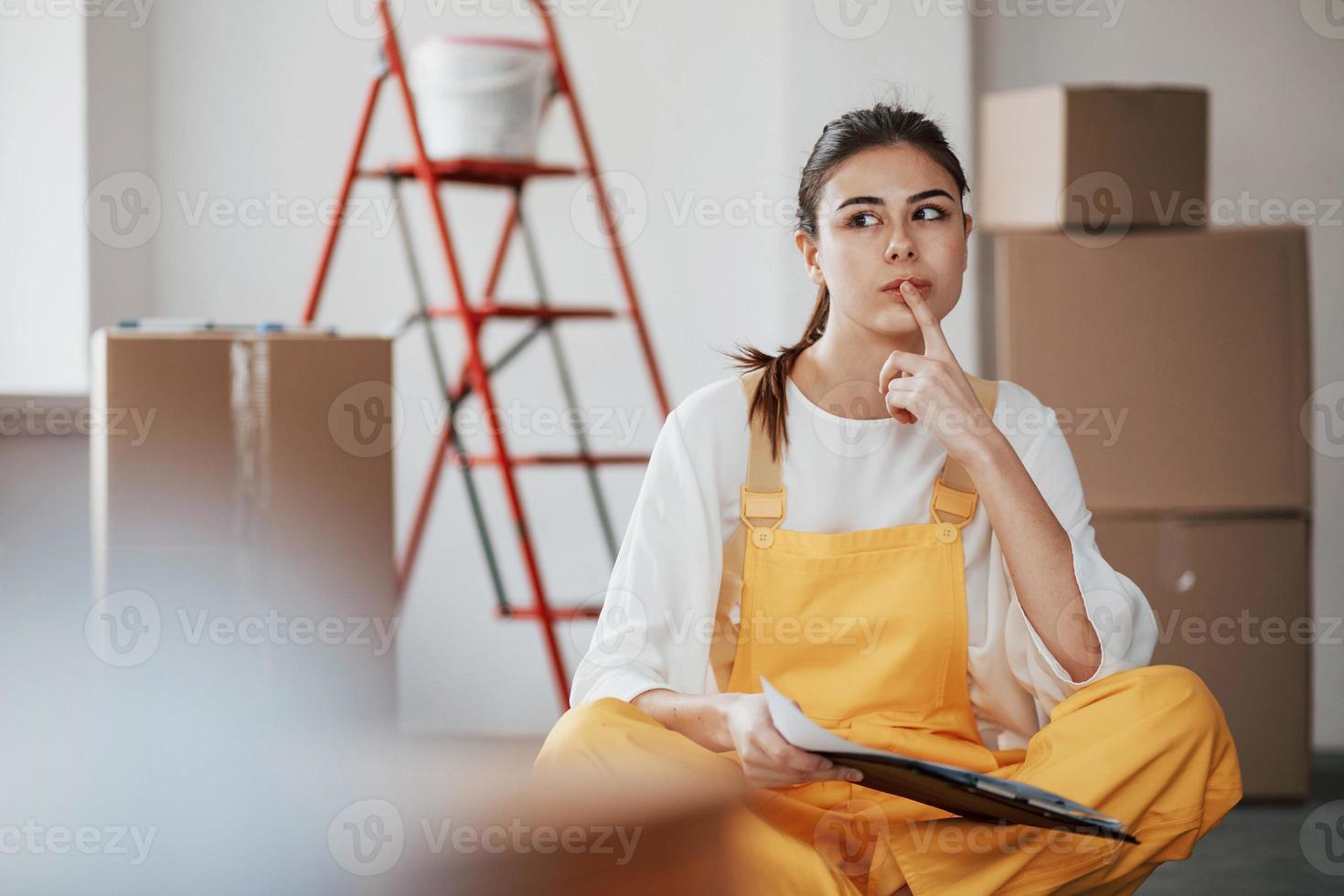 nieuwe woning moet worden gerepareerd. jonge brunette in de kamer met witte muren en daglicht dat uit het raam komt foto