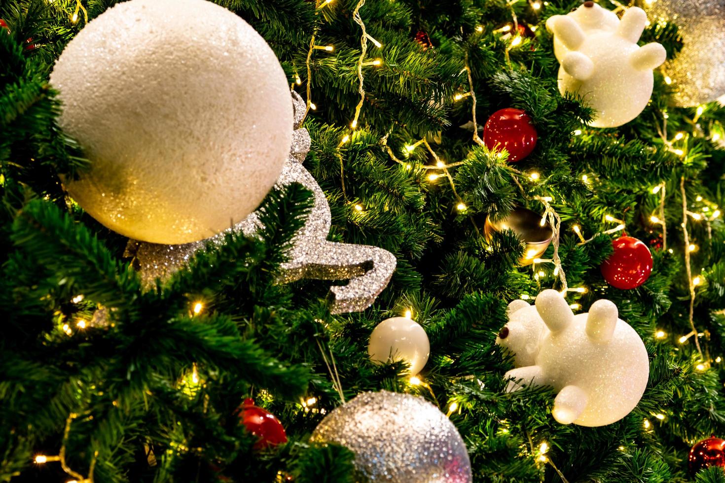 close-up kerstboomversiering met rode, gouden, zilveren en witte ballen, zilveren ster en witte rendieren. Kerstmis achtergrond. kerstmis en gelukkig nieuwjaar achtergrond. kleurrijke bal op kerstboom. foto