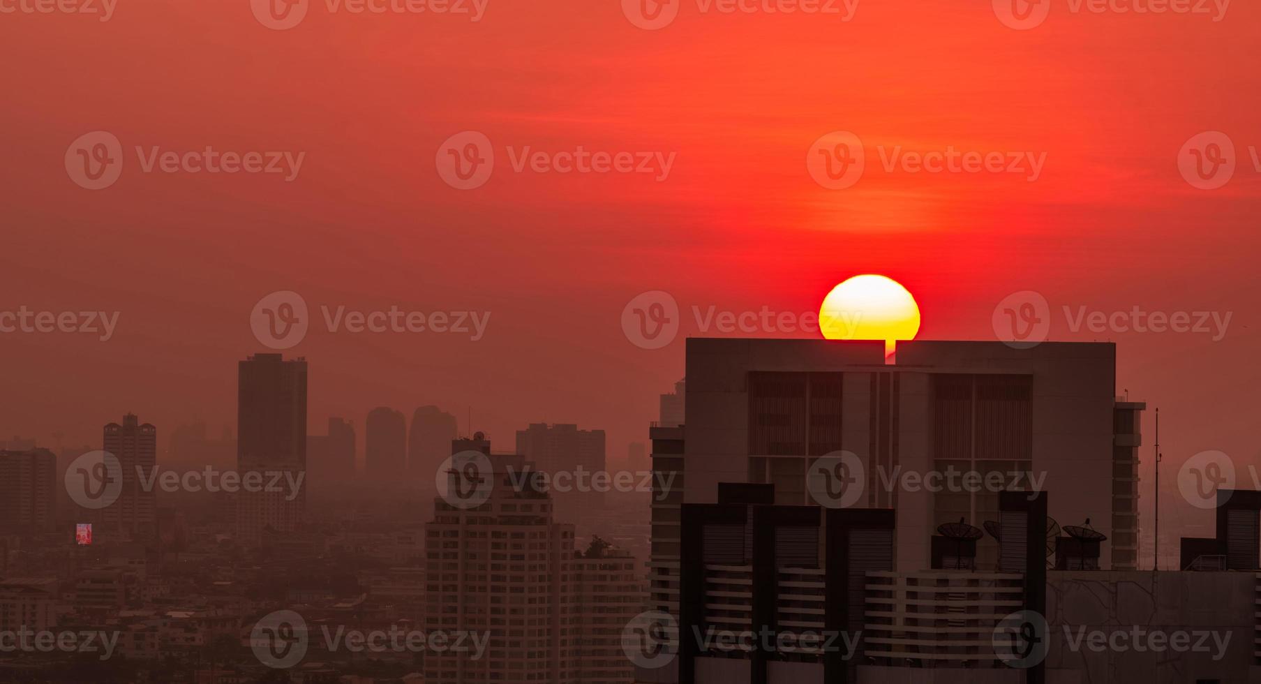 stadsgezicht in de ochtend met zonsopganghemel en luchtvervuiling. fijnstof van pm 2.5 dekken stad. stadsgezicht met overvol woongebouw. stedelijke zonsopgang met grote rode zon. smog in de lucht. ongezond. foto