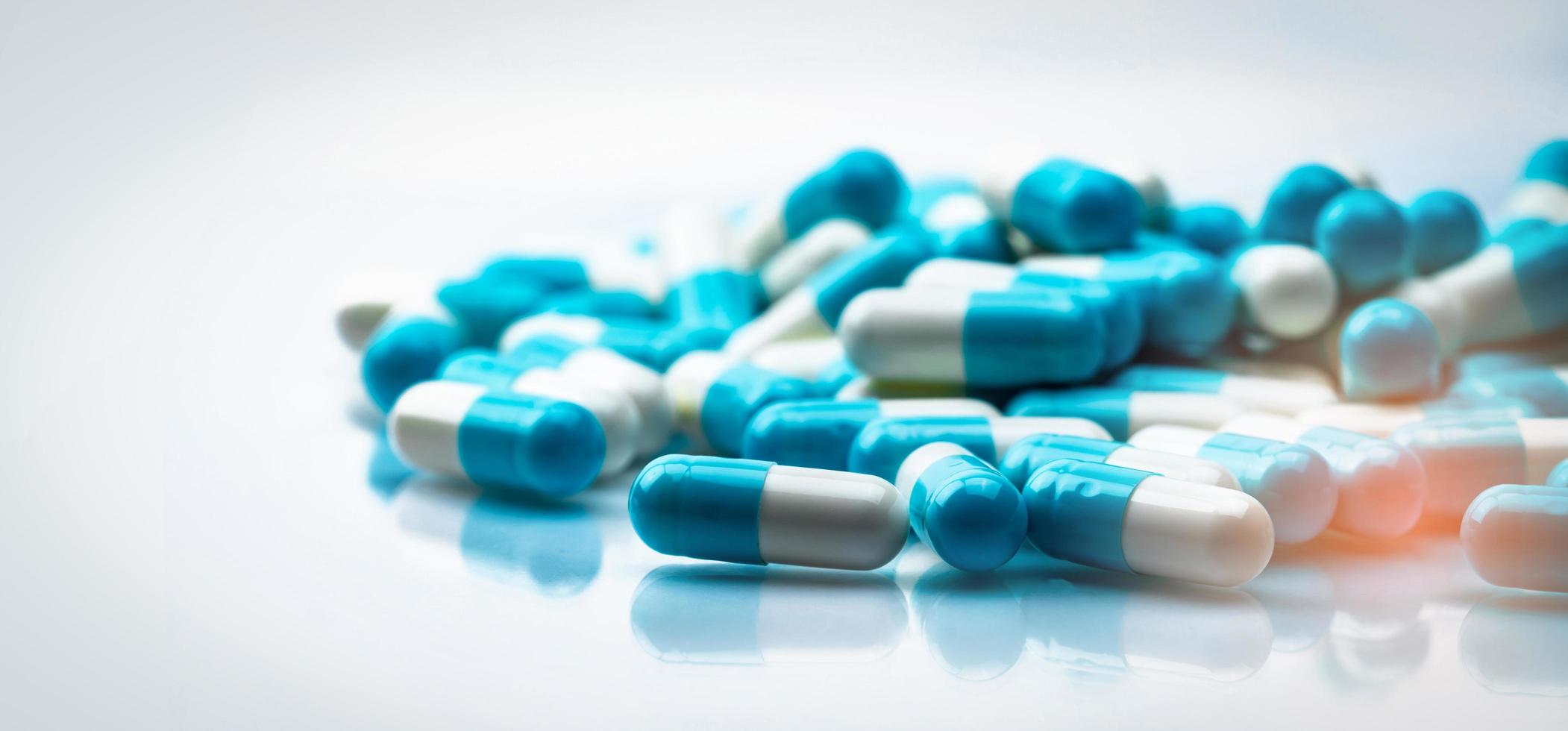 selectieve focus op blauwe en witte capsules pil op witte achtergrond. resistentie tegen antibiotica. antimicrobiële capsulepillen. farmaceutische industrie. apotheek drogisterij producten. farmacie. foto