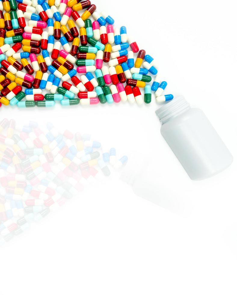 antibiotica capsules morsen uit pil fles op witte achtergrond met kopie ruimte en schaduwen. geneesmiddelresistentie concept. antibiotica drugsgebruik met een redelijk en wereldwijd gezondheidsconcept. foto