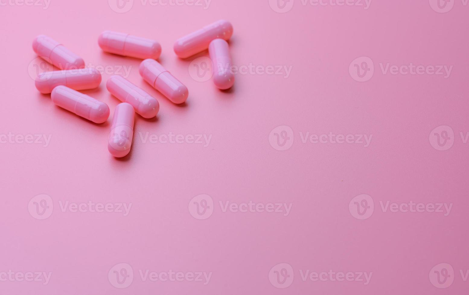 roze capsulepillen op roze achtergrond. vrouw ziektekostenverzekering budget. apotheek winkel banner. farmaceutische industrie. vitamines en supplementen. capsule pillen industrie. blijheidspillen. pillen van liefde. foto