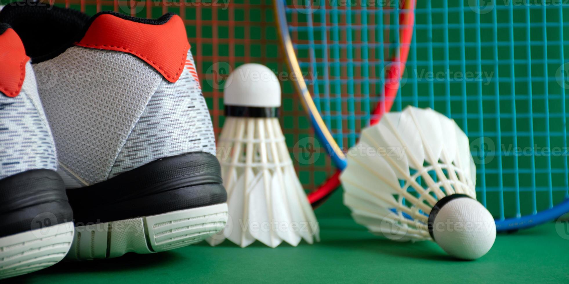 badmintonsportuitrusting op groene vloer van badmintonveldshuttles, rackets, schoenen, selectieve focus op shuttles, badmintonsportliefhebber over het hele wereldconcept. foto