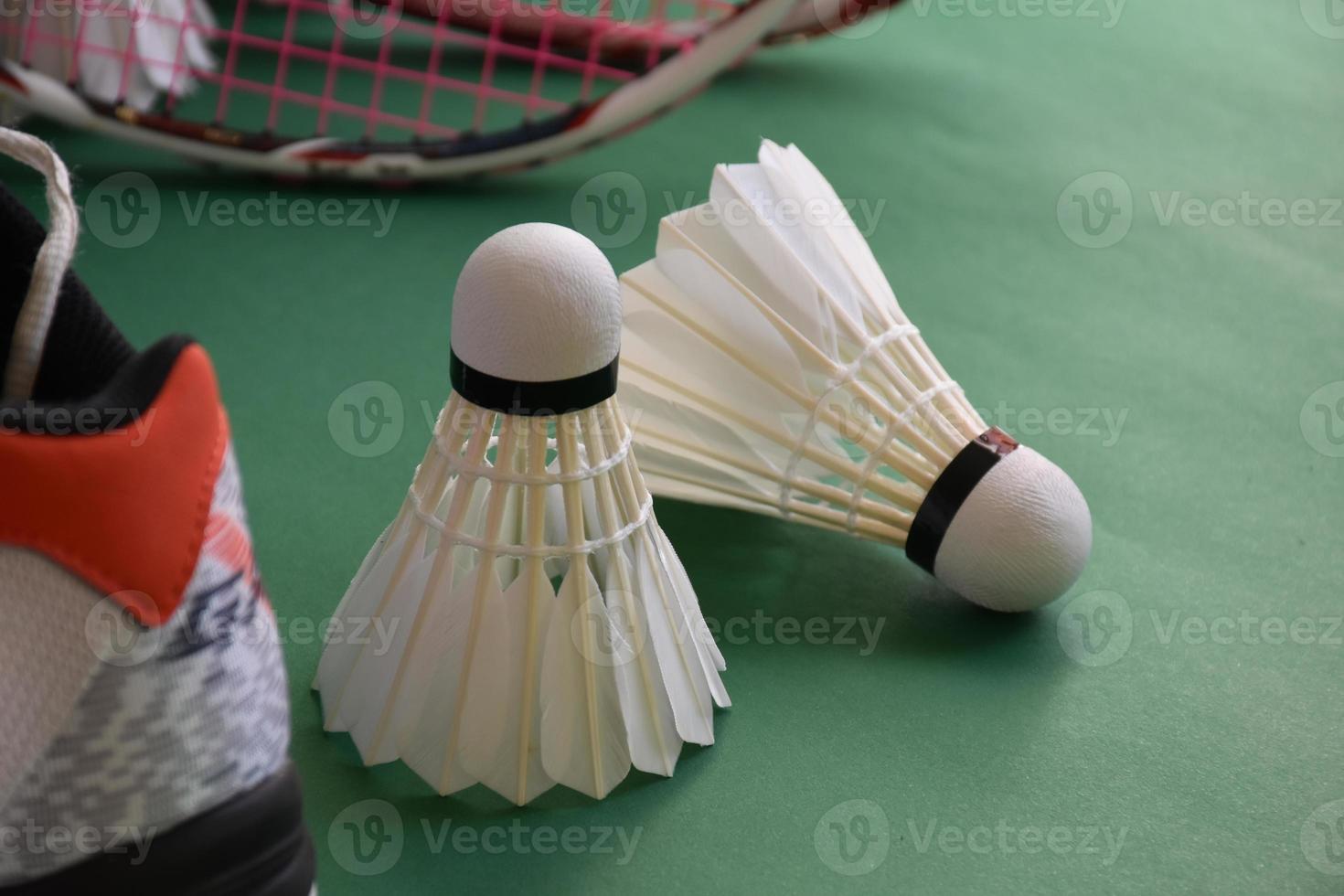 badmintonsportuitrusting op groene vloer van badmintonveldshuttles, rackets, schoenen, selectieve focus op shuttles, badmintonsportliefhebber over het hele wereldconcept. foto