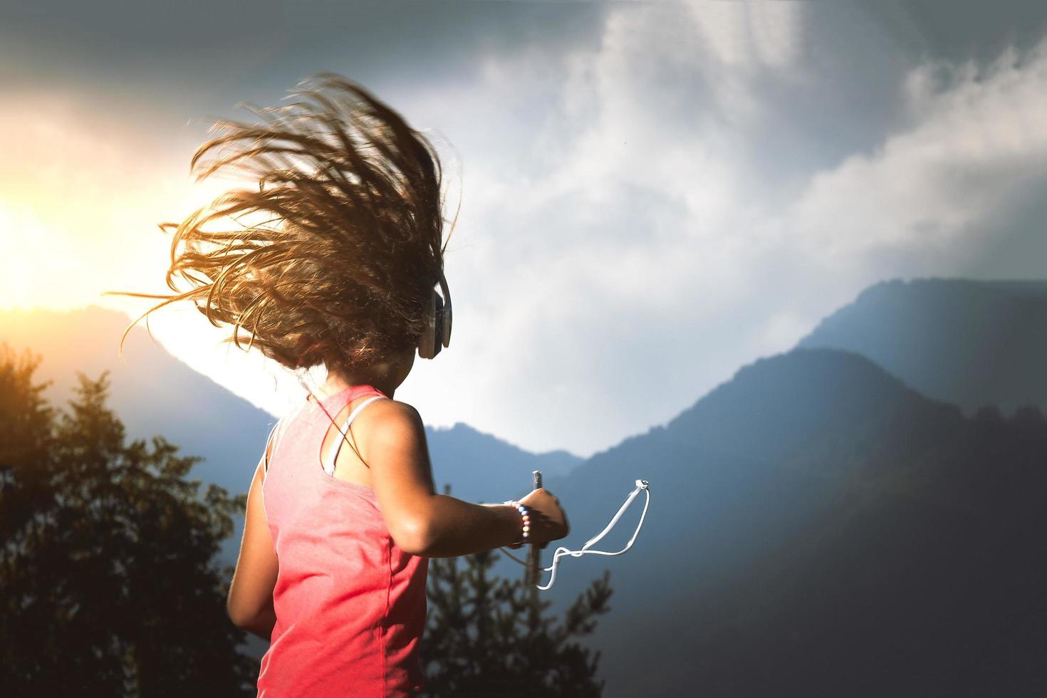 klein meisje met haar haren in de wind luistert naar muziek met speler en koptelefoon foto