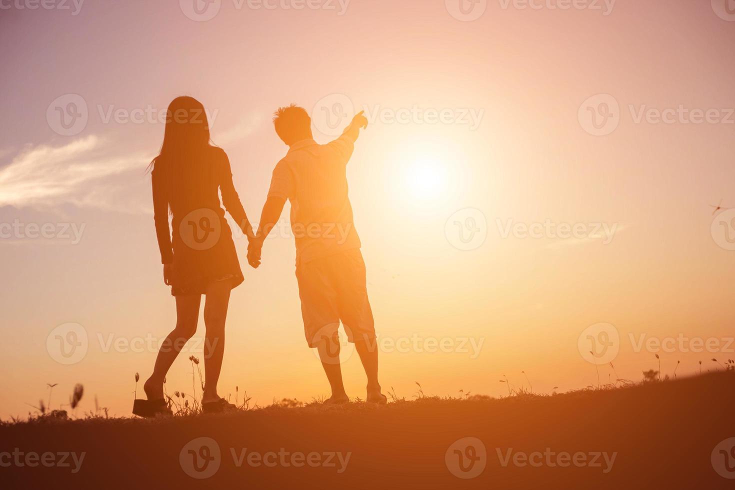 silhouet van een man en vrouw hand in hand met elkaar, samen wandelen. foto