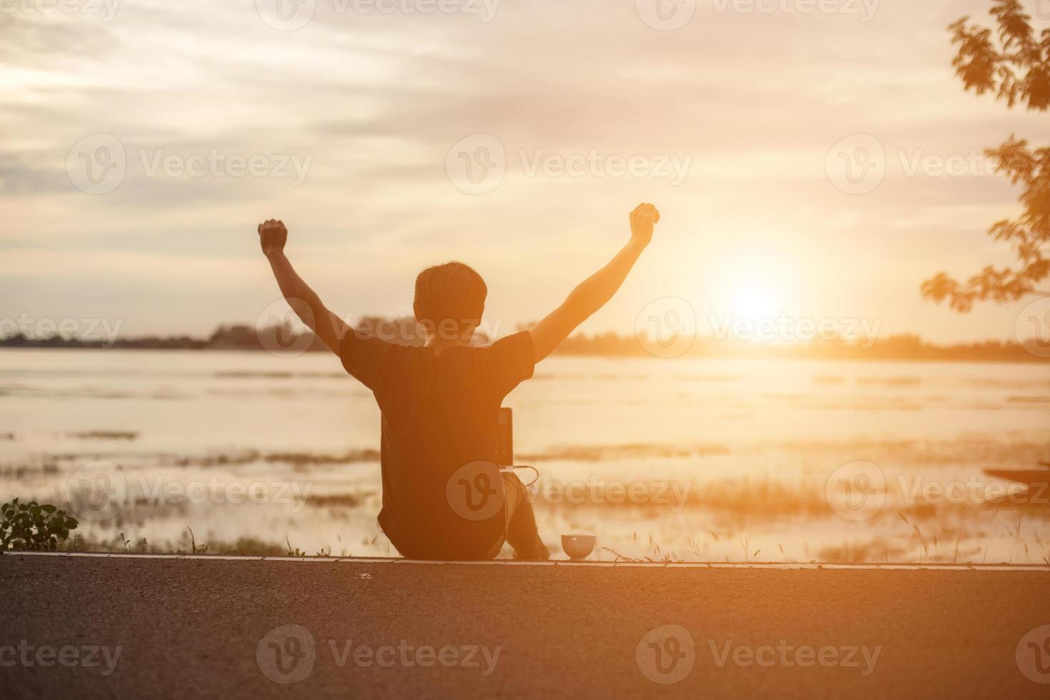 succesvolle sportman die armen op gouden hemel achtergrondverlichting zonsondergang zomer opheft na cross running. fitness mannelijke atleet met armen omhoog om doelen te vieren na het sporten en buiten sporten. foto