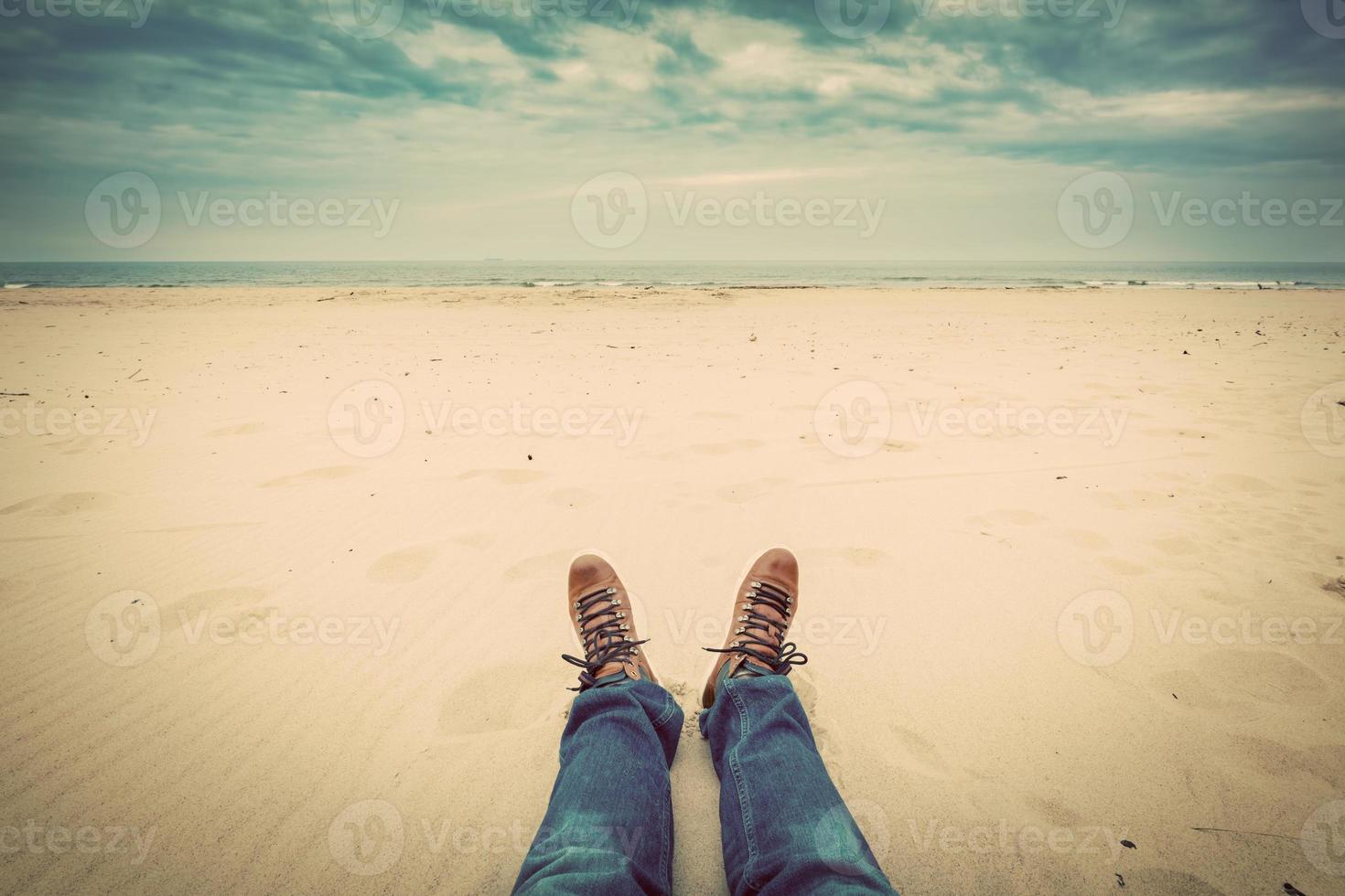 first person perspectief van mannenbenen in spijkerbroek op het herfststrand foto