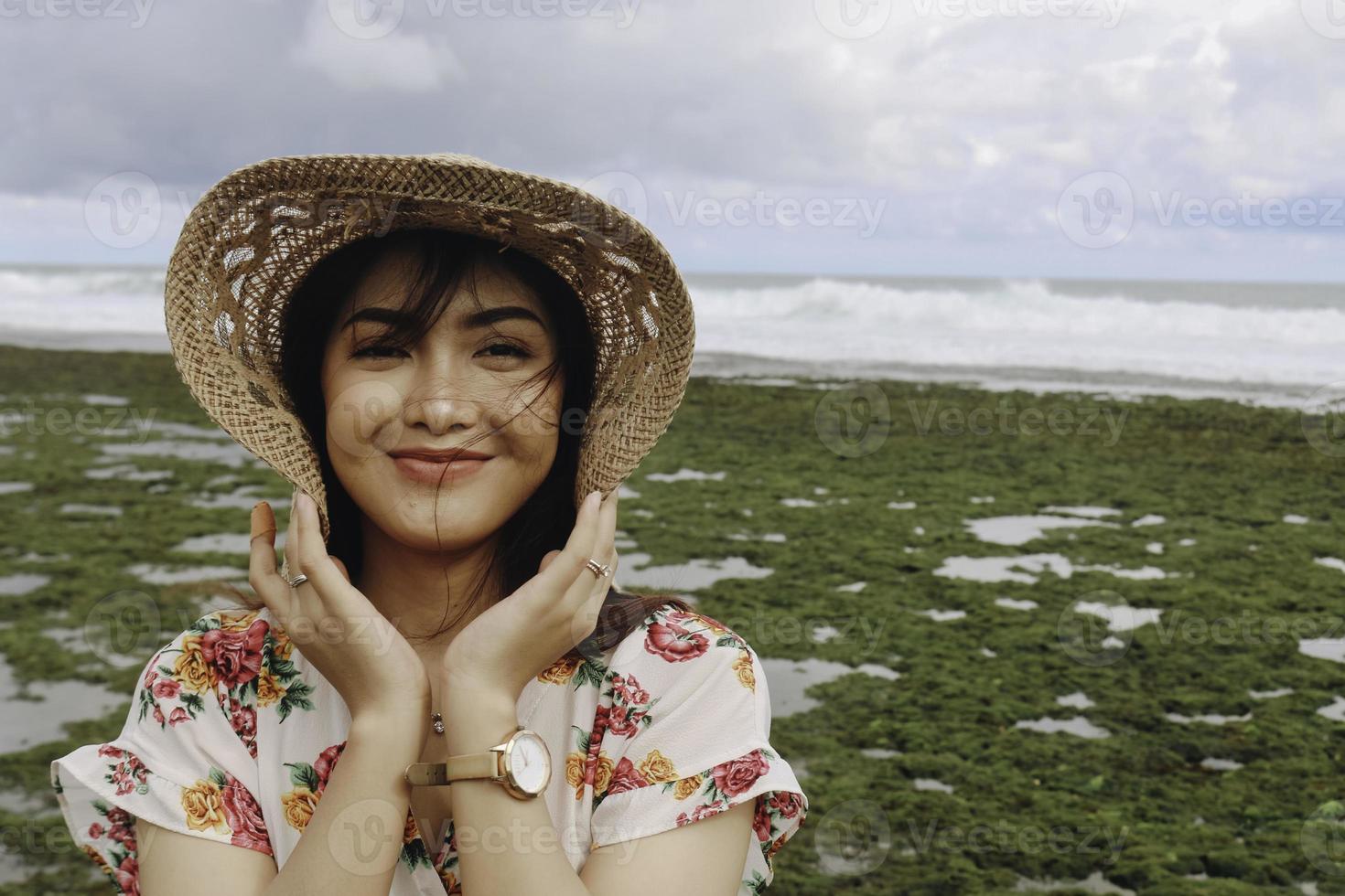 een jong Aziatisch meisje met een strandhoed ontspant op het blauwe hemelstrand bij gunungkidul, indonesië foto