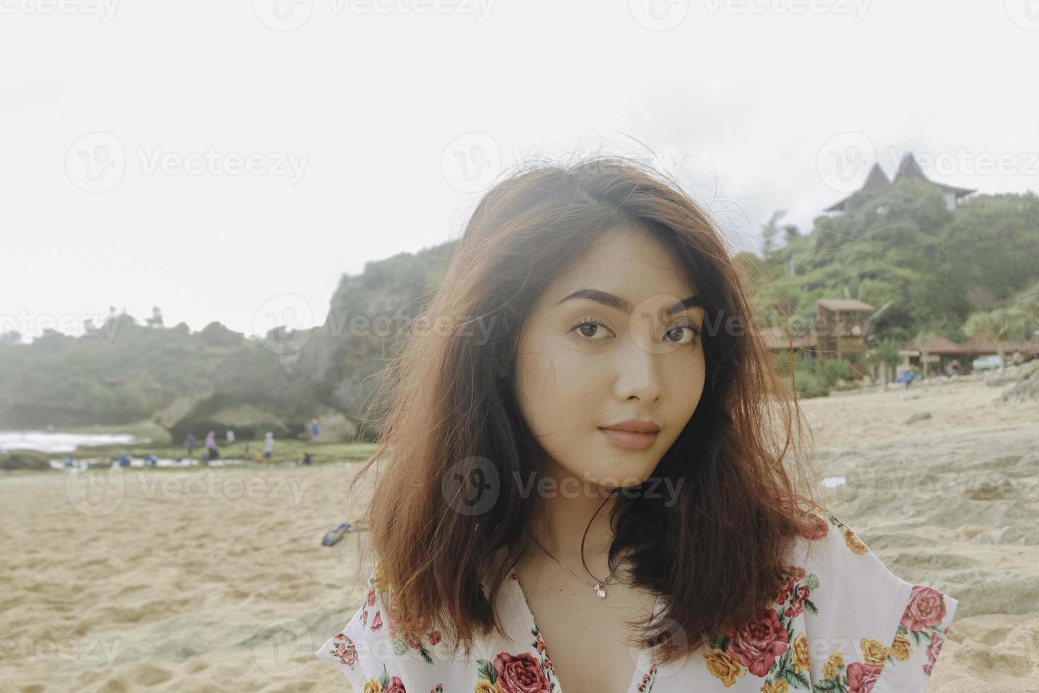 een jonge aziatische vrouw die zit te chillen op het strandzand, gunungkidul, indonesië foto