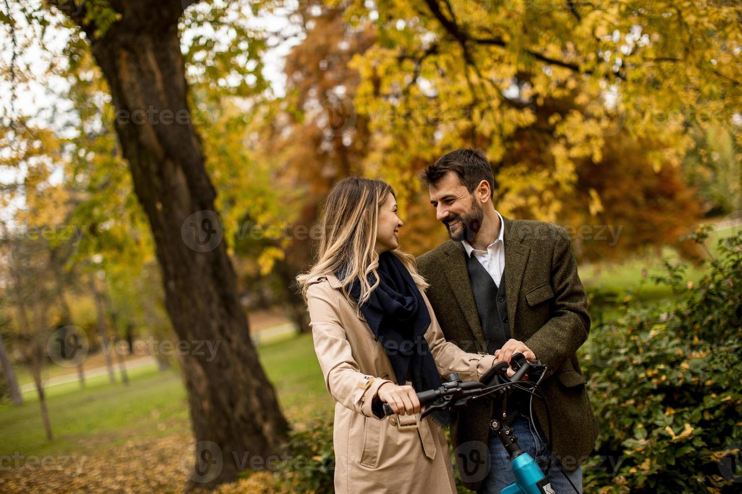 jong stel in het herfstpark met elektrische fiets foto