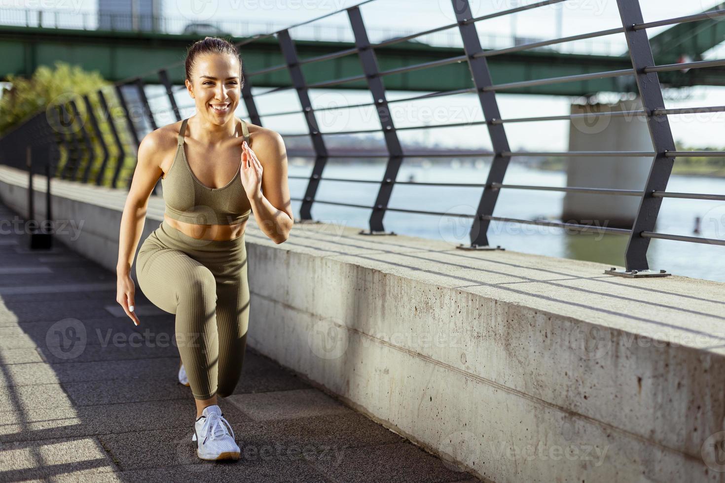 jonge vrouw in sportkleding die zich uitstrekt over een rivierpromenade foto