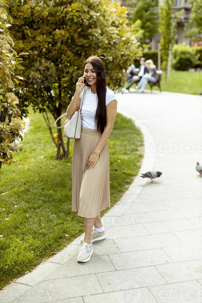 jonge vrouw met behulp van een mobiele telefoon tijdens het wandelen op straat foto