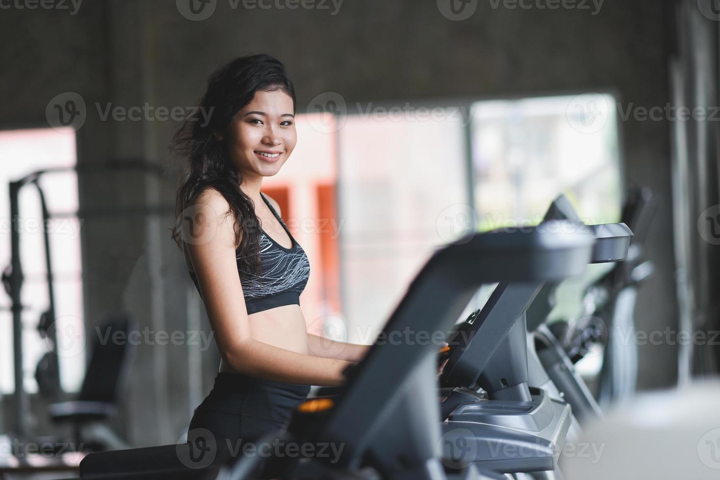 Aziatische sport vrouw draait op de loopband in fitnessclub. cardio workout. gezonde levensstijl, man training in de sportschool. sport hardloopconcept foto