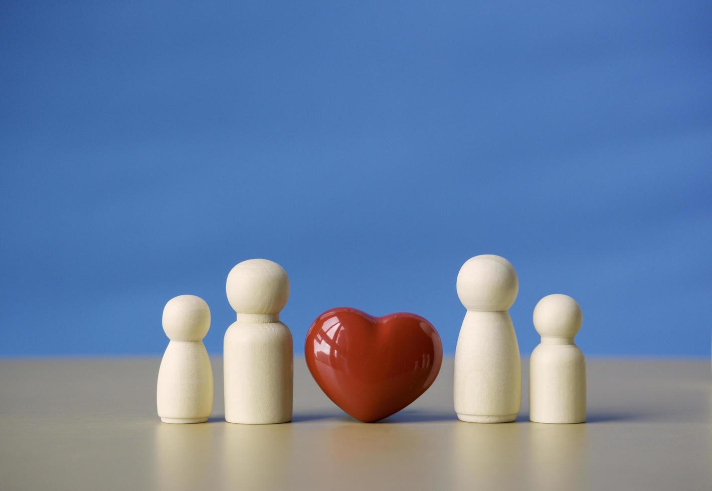 familie houten figuur staande in de buurt van rood hartsymbool. concept van liefde voor relatie familie, paar leven en geluk met blauwe achtergrond. foto