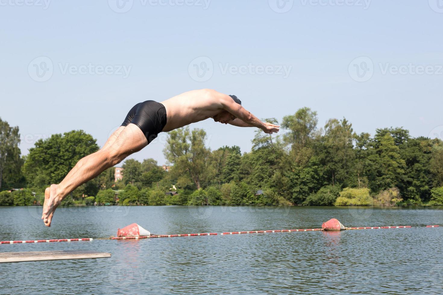 man springen van duikplank bij zwembad foto