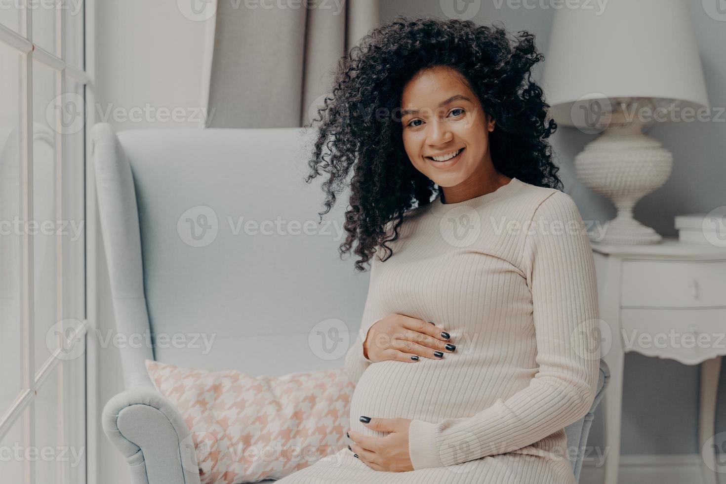 mooie zwangere afrikaanse vrouw geniet van zwangerschap, tijd thuis doorbrengend foto