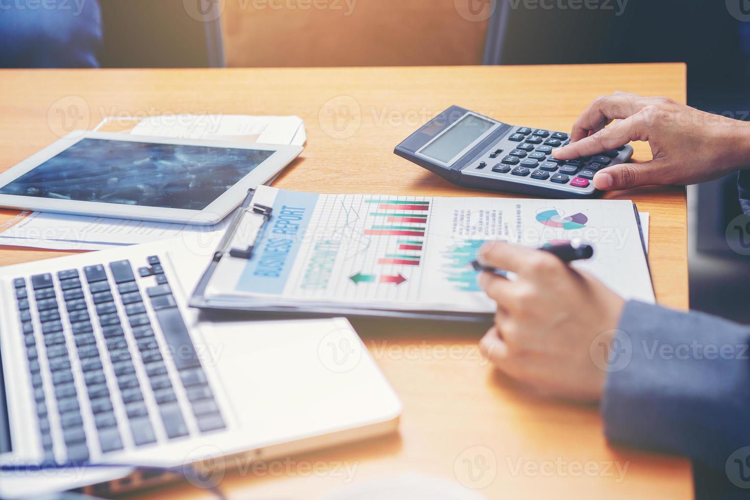 vrouw accountant werkt aan bureau met behulp van rekenmachine voor het berekenen en controleren van het financiële rapport. geselecteerde focus foto