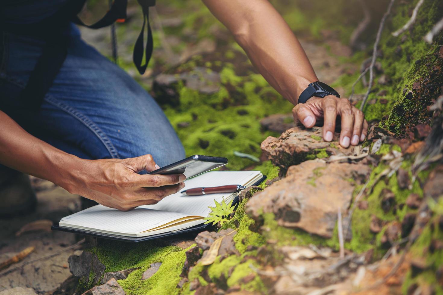 bioloog of botanicus die informatie opneemt over kleine tropische planten in het bos. het concept van wandelen om botanische tuinen te bestuderen en te onderzoeken door naar informatie te zoeken. foto