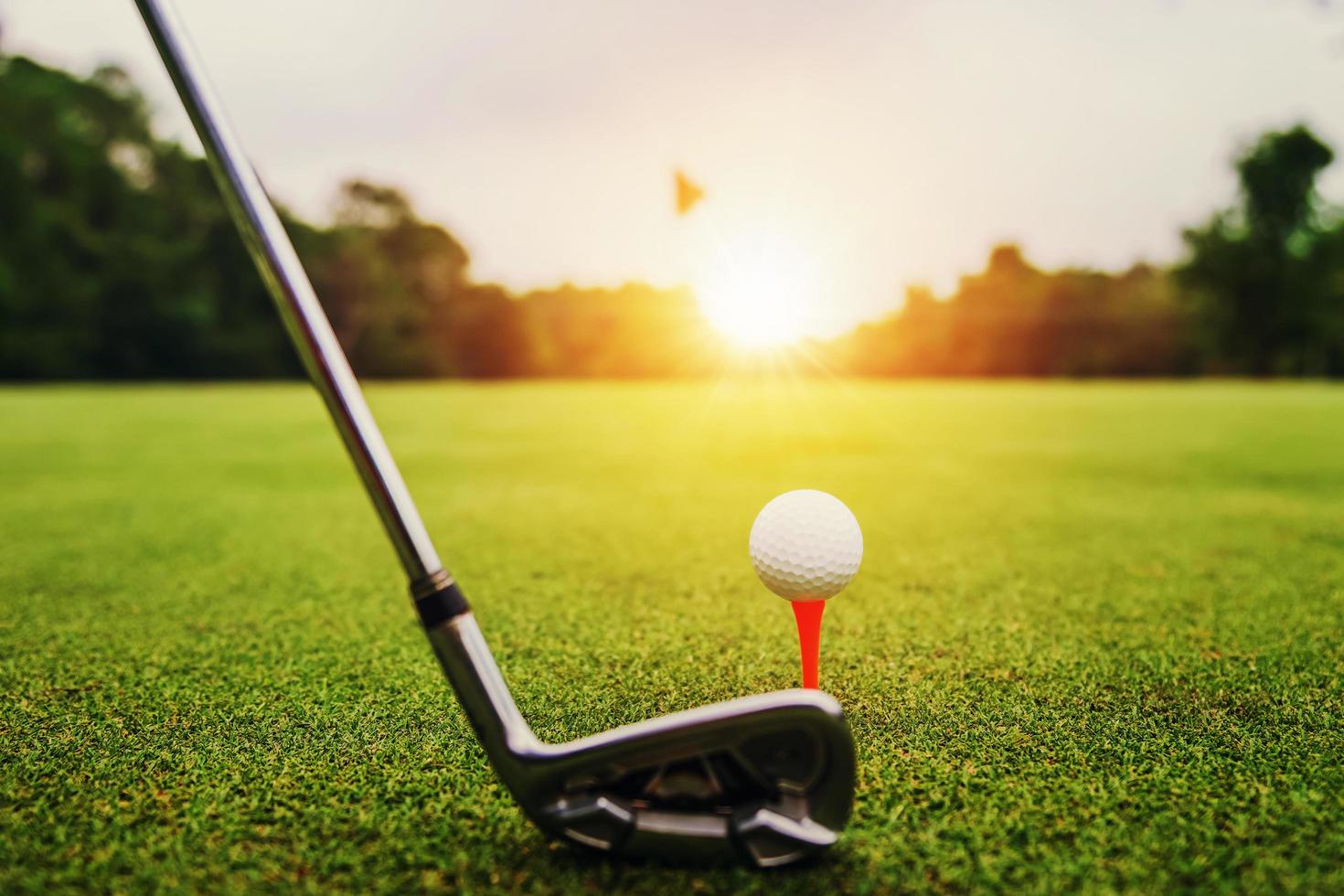 close-up golfclub en golfbal op groen gras met zonsondergang foto