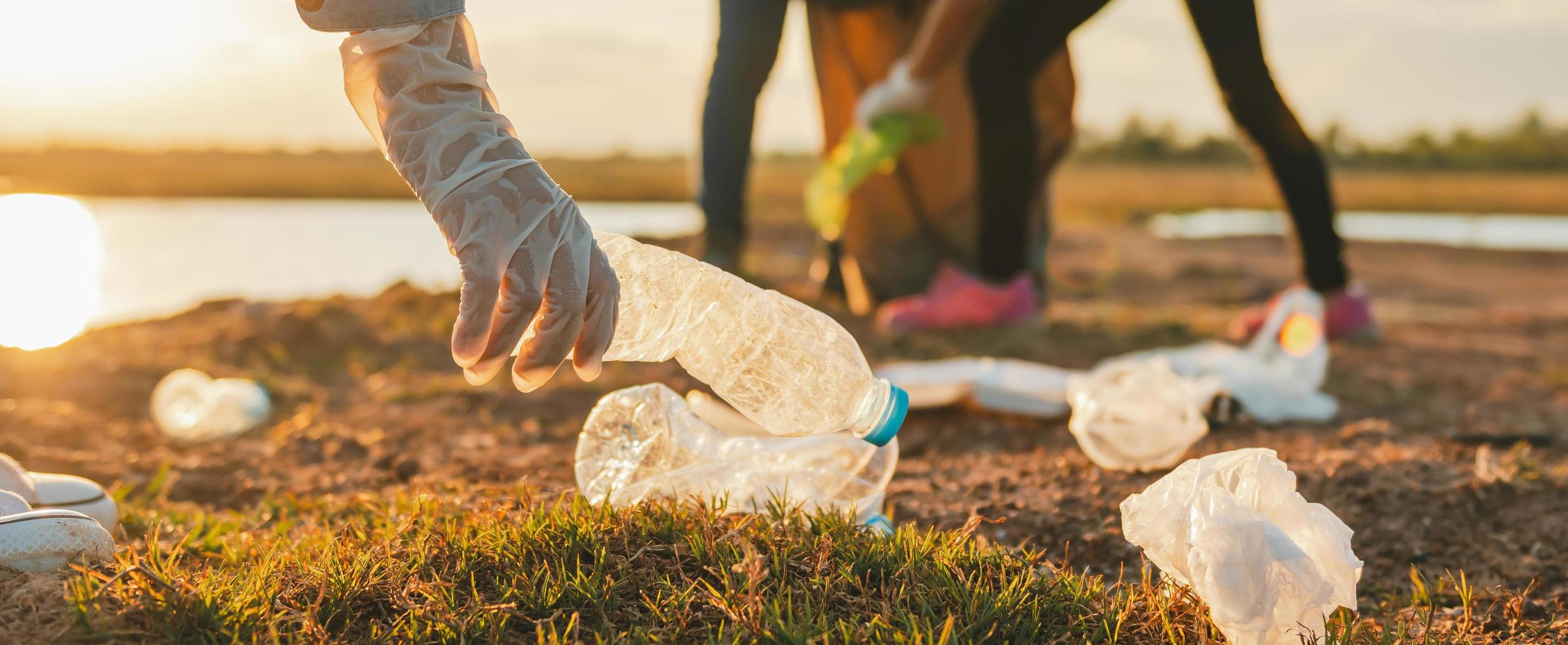 vrouw die vuilnis plastic fles met de hand oppakt om in het park schoon te maken foto