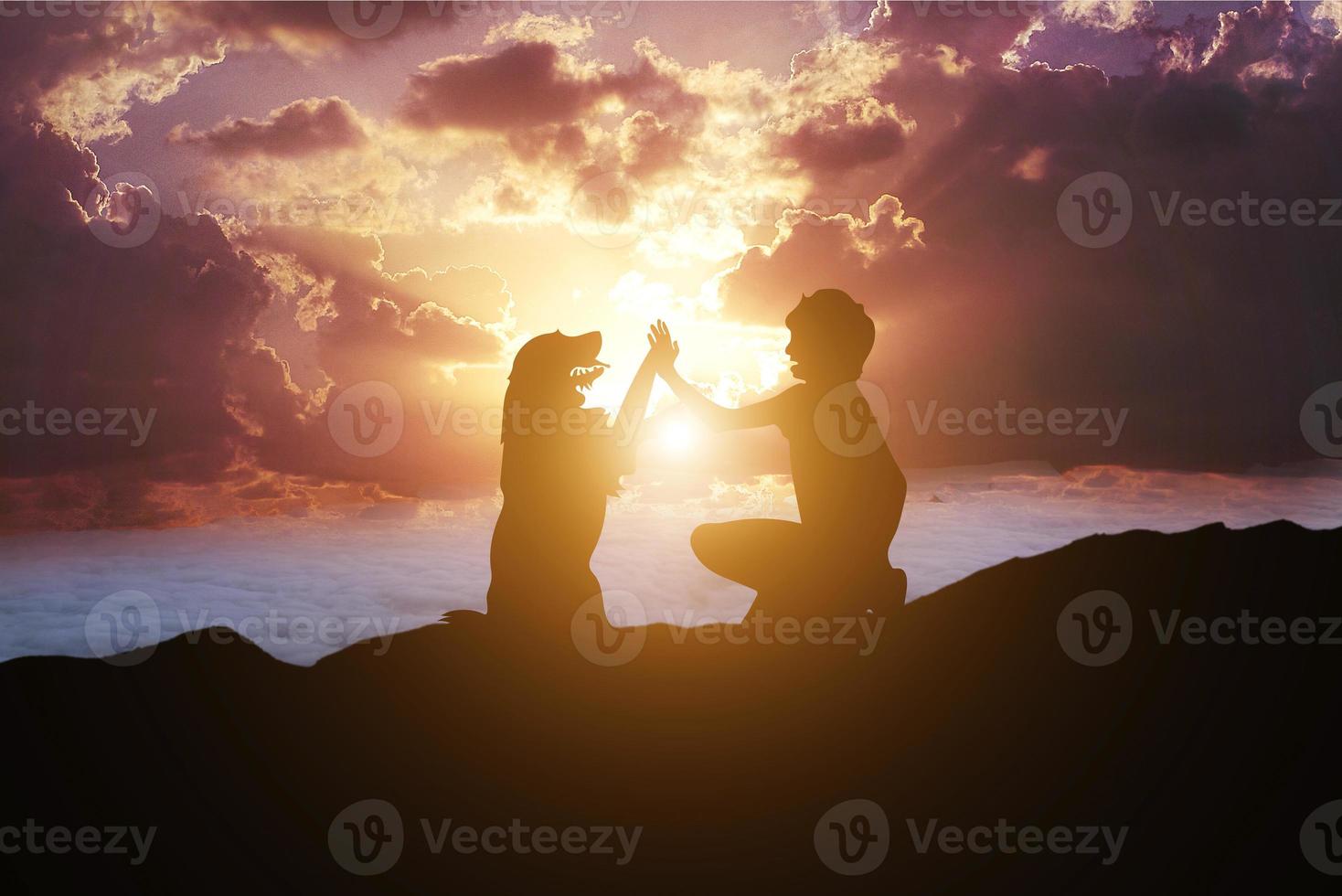 vriendschap tussen een man en een hond bovenop een berg bij zonsondergang foto