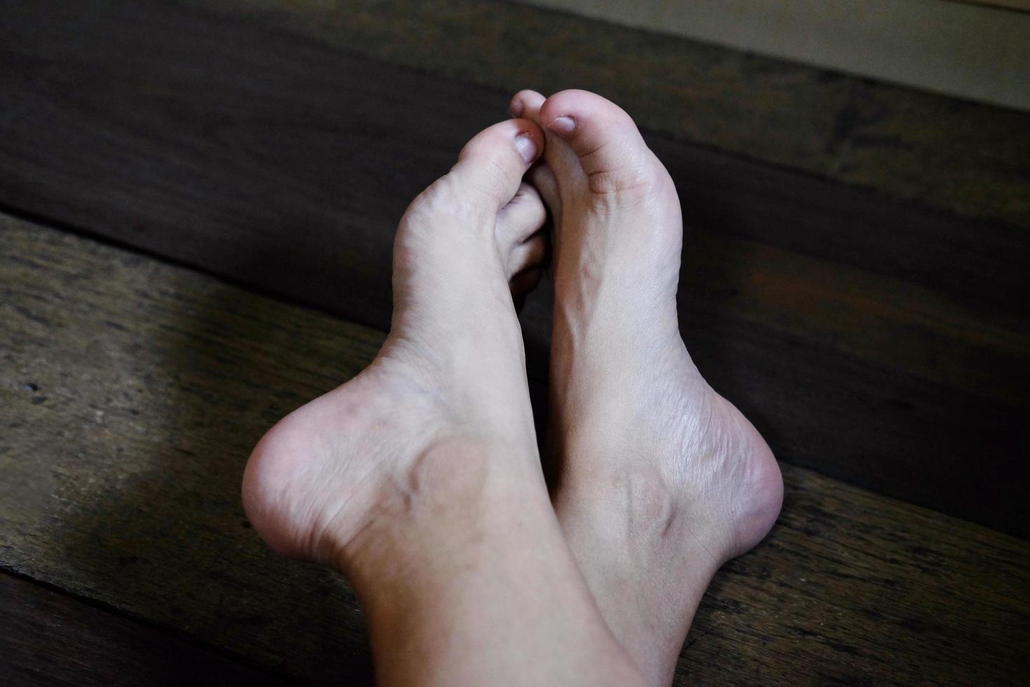 gesloten vrouwelijke voeten met franse nagels op houten vloer, gezonde zorg en medisch concept foto