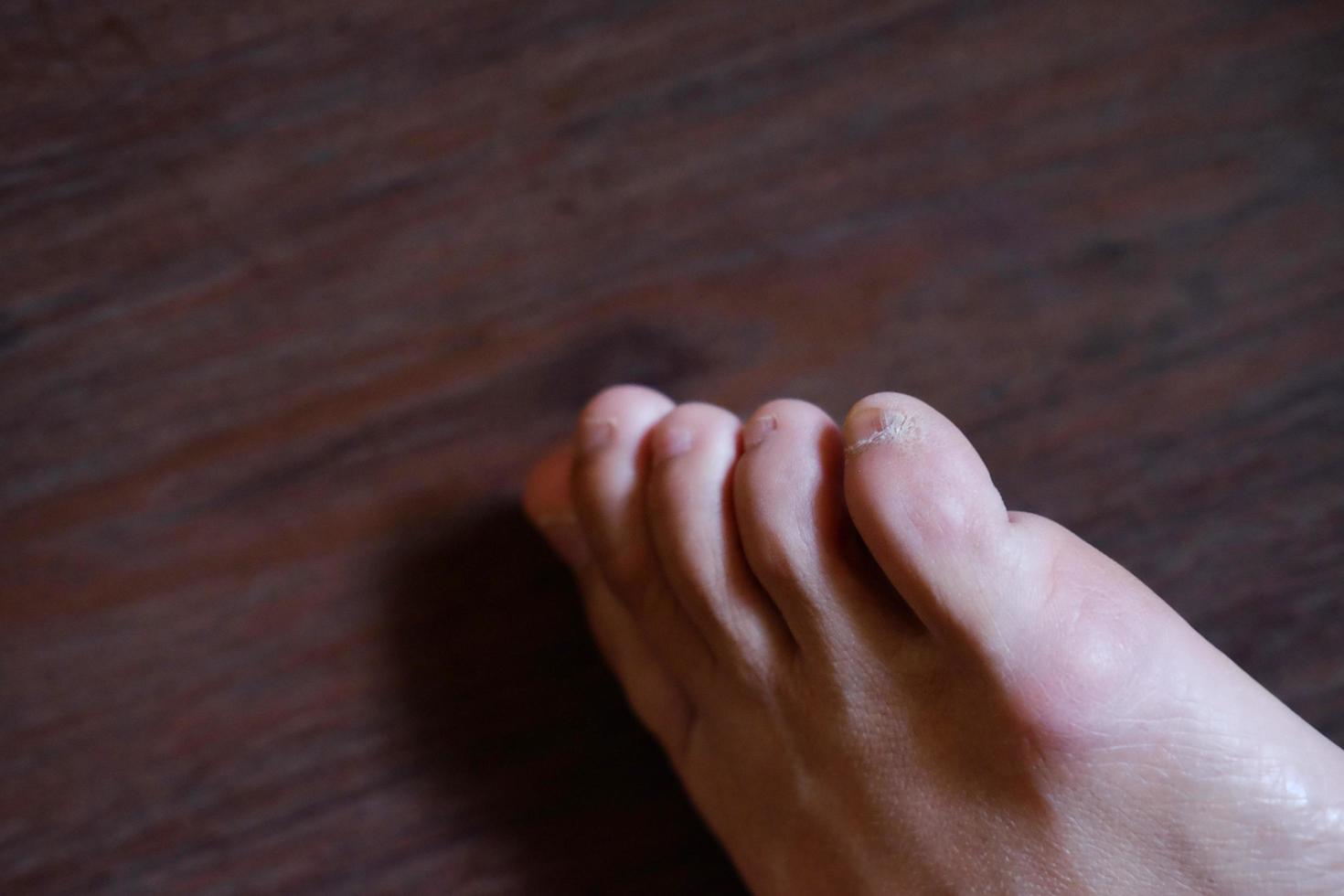 gesloten vrouwelijke voeten met franse nagels op houten vloer, gezonde zorg en medisch concept foto