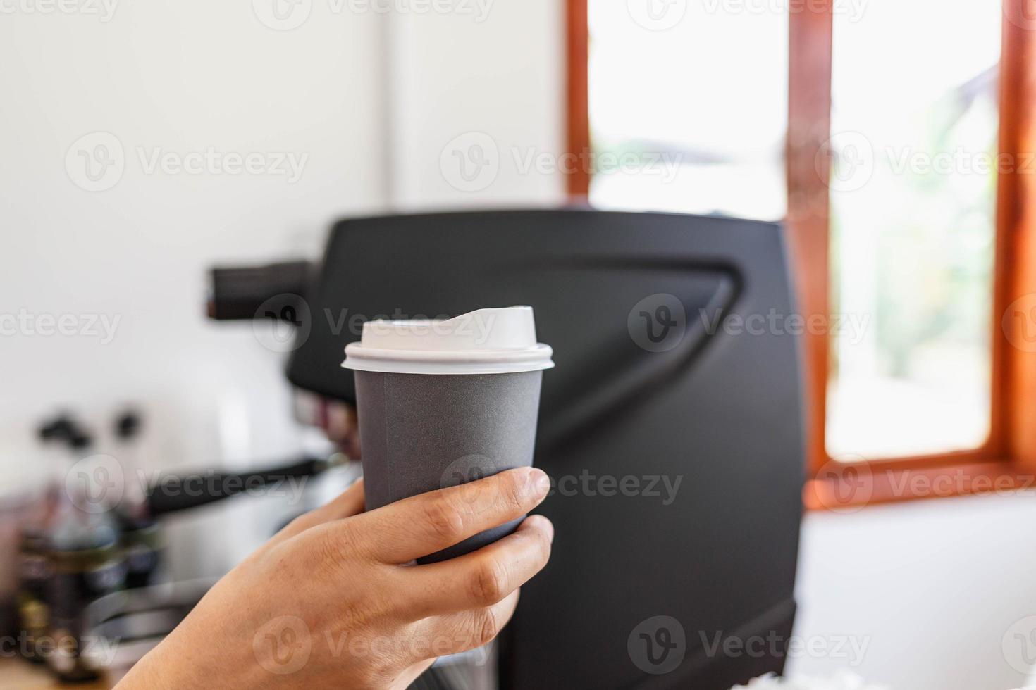 hete koffie in een papieren beker in de hand van een barista. foto
