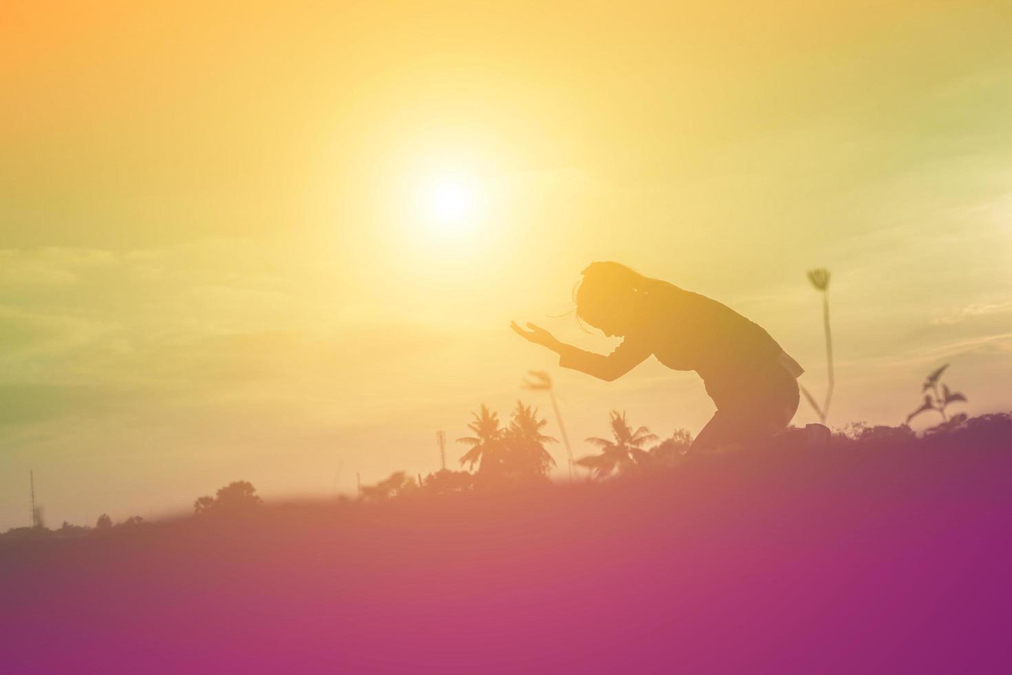 silhouet van een vrouw die bidt over een prachtige hemelachtergrond foto