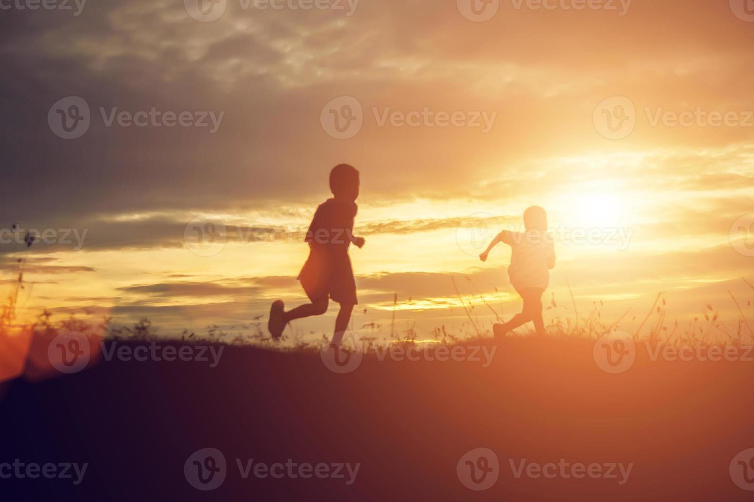 silhouet van een gelukkige kinderen en een gelukkige zonsondergang foto