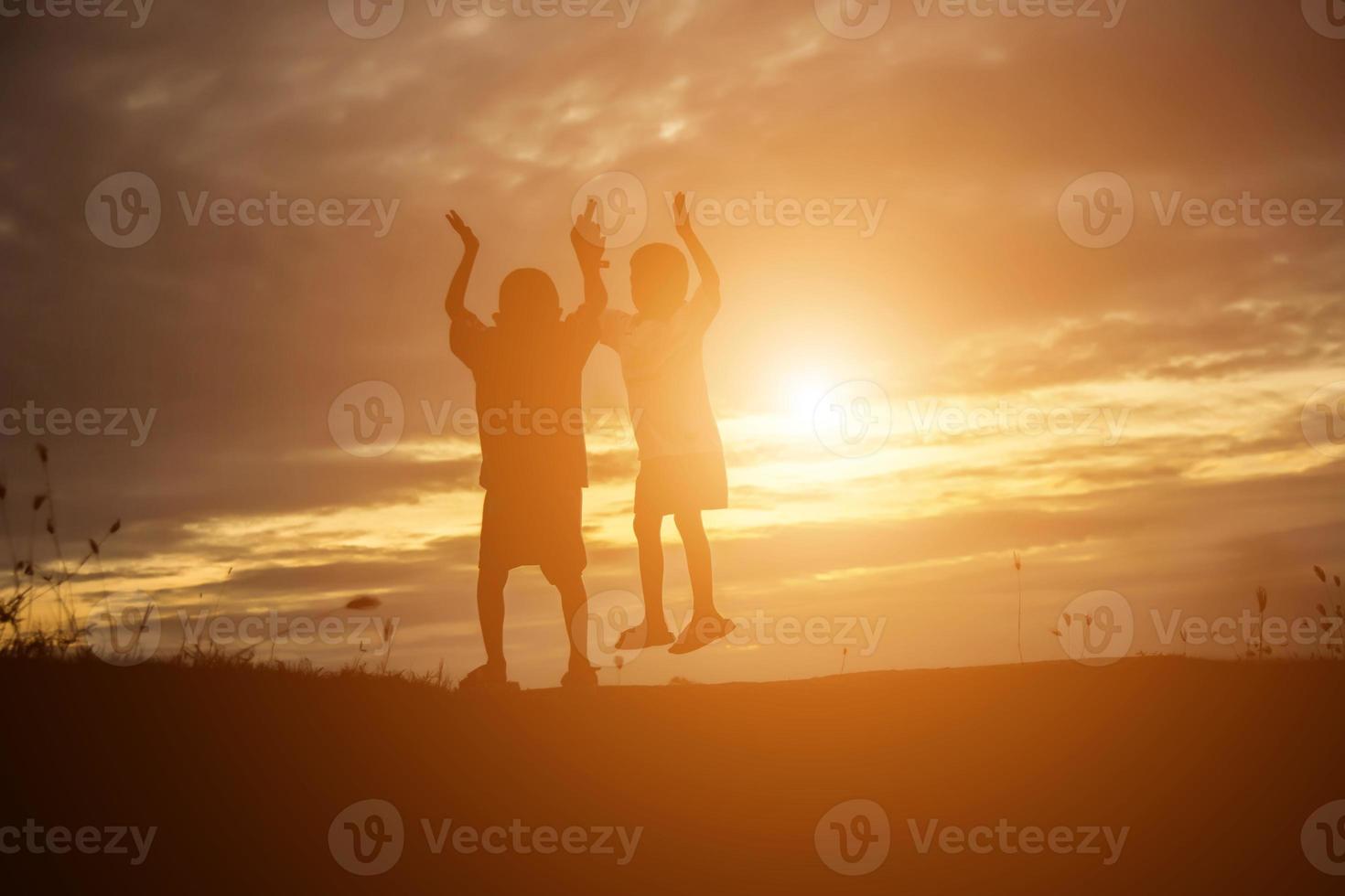 silhouet van een gelukkige kinderen en een gelukkige zonsondergang foto