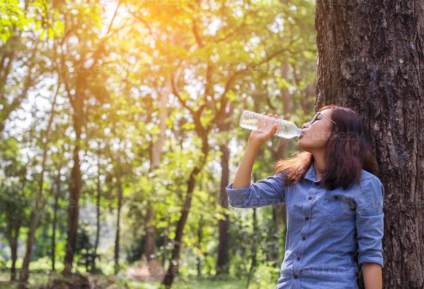 mooie jonge vrouw die 's ochtends water drinkt nadat ze klaar is met joggen foto