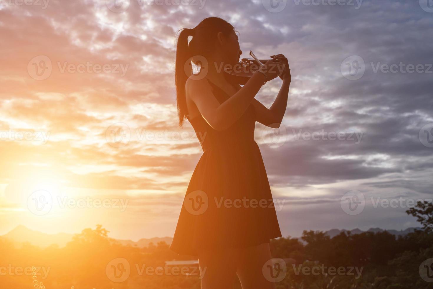 jonge vrouw die viool speelt met bergen op de achtergrond foto
