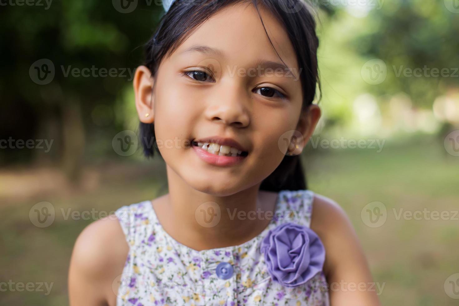 klein schattig Aziatisch meisje dat zich onder de paarse bloemveldzondag bevindt. vrijheid genieten met de natuur. foto
