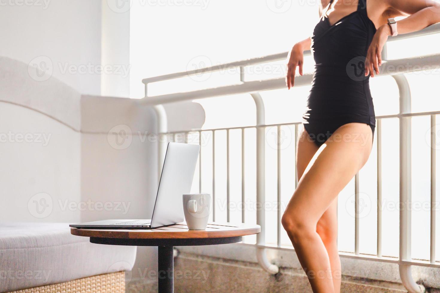 vrouw in zwempak met opengeklapte laptop op tafel. foto