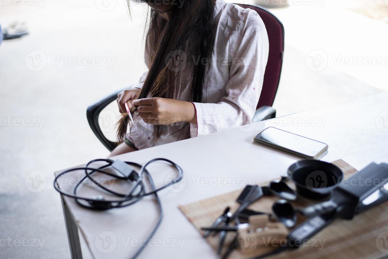 portret van een verdrietig meisje met lang haar dat een probleem heeft met haar uiteinden en beide handen houden de uiteinden van haar haar vast. perfecte begrip. foto