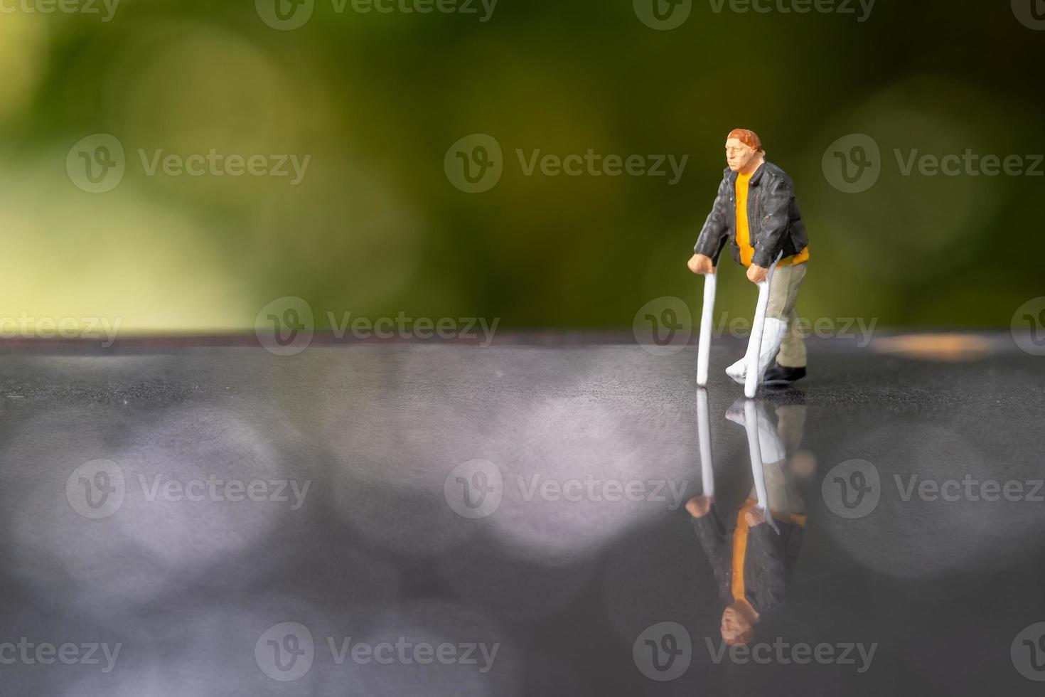 miniatuur mensen man met gebroken been gebruikt kruk om te lopen foto