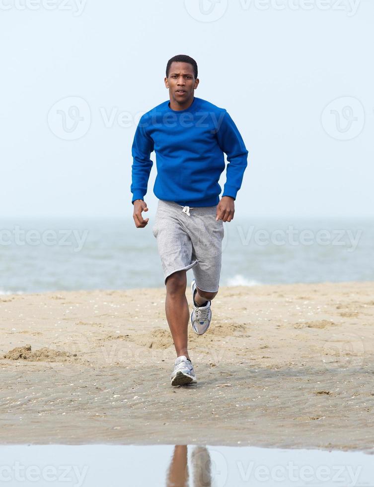 Afro-Amerikaanse man joggen op strand foto
