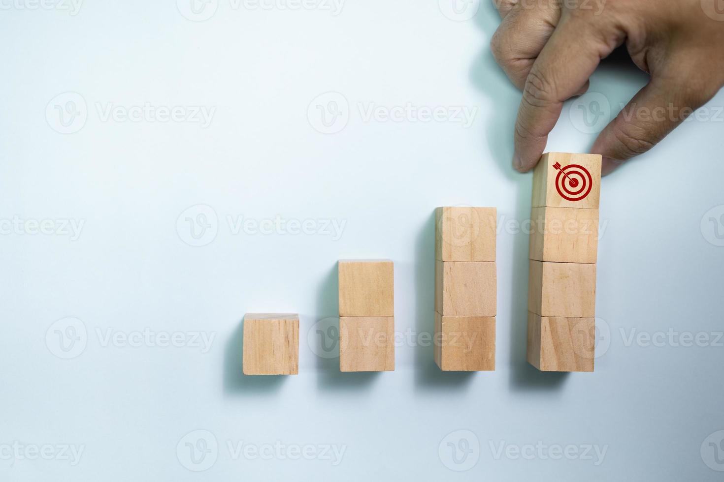 bovenaanzicht handplaats houten blokken ingesteld op stap met pictogrampijl naar doel. concept voor groeiactiviteiten en targeting. foto